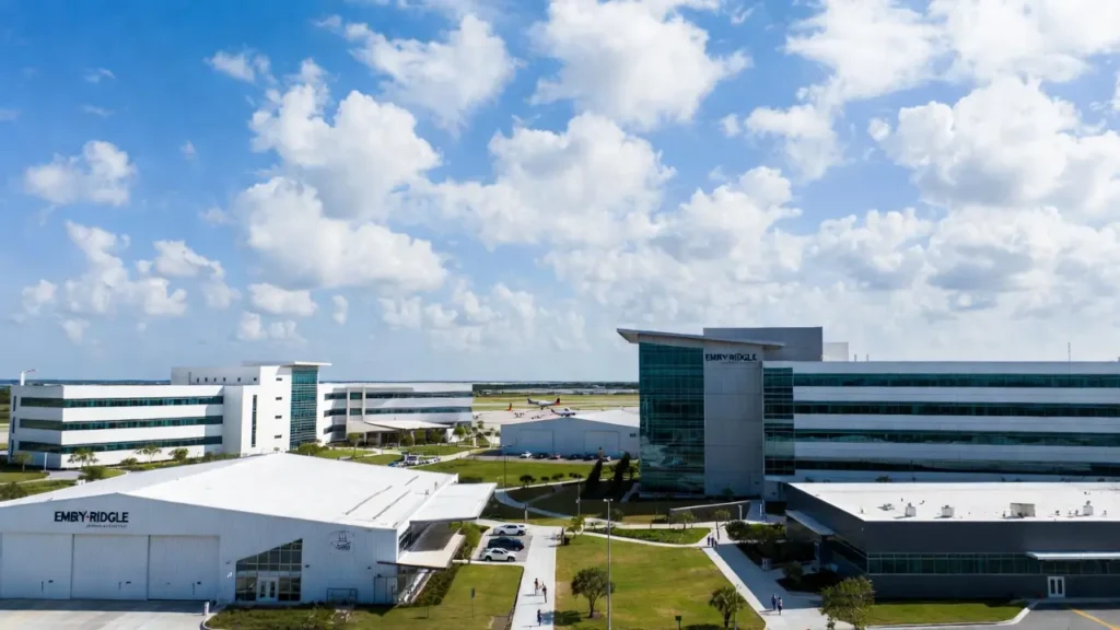 Wide aerial shot of Embry-Riddle Aeronautical University in Florida, featuring contemporary structures, hangars, and planes in the distance.